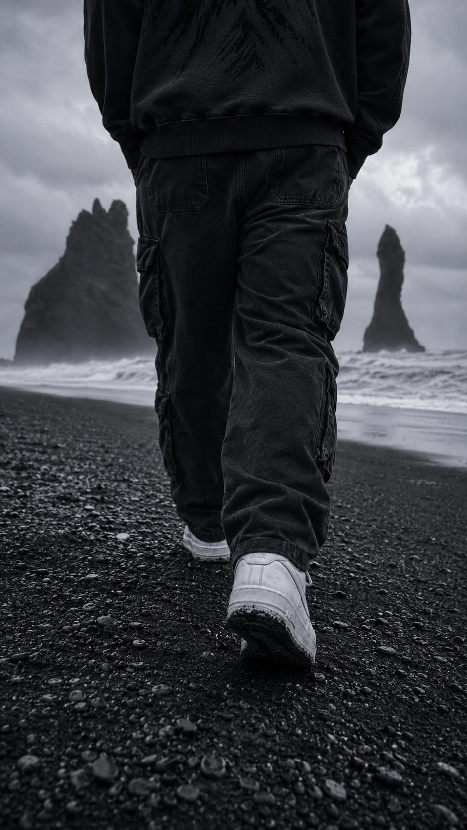 A lone figure walking the black sand coast